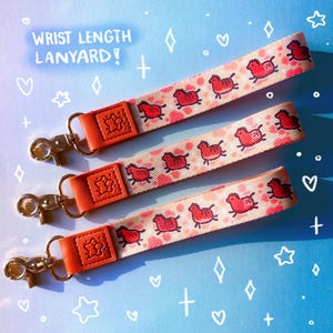 Peut inclure: Trois cordons de poignet avec un motif répétitif de petits chevaux rouges sur fond rose clair. Chaque cordon possède une patte en similicuir orange vif gaufrée d'une étoile et un fermoir mousqueton pivotant en métal doré.