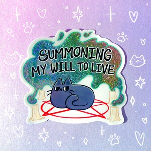 May include: A sticker featuring a blue cat with sunglasses sitting on a red pentagram, surrounded by candles. The text "SUMMONING MY WILL TO LIVE" is displayed in bold, black letters against a glittery green and blue background.