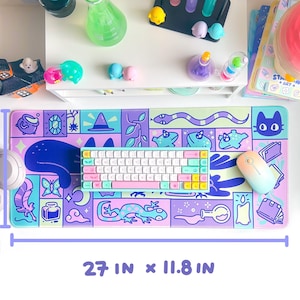 Puede incluir: Una alfombrilla de escritorio colorida con un dise&ntilde;o caprichoso que presenta un gato, una serpiente, un lagarto, una botella de poci&oacute;n, una mariposa y un sombrero de bruja. La alfombrilla mide 27 pulgadas por 11,8 pulgadas.