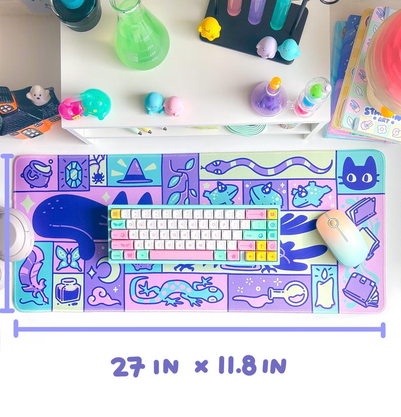Puede incluir: Una alfombrilla de escritorio colorida con un dise&ntilde;o caprichoso que presenta un gato, una serpiente, un lagarto, una botella de poci&oacute;n, una mariposa y un sombrero de bruja. La alfombrilla mide 27 pulgadas por 11,8 pulgadas.