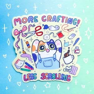 May include: A colorful sticker with the text "MORE CRAFTING! LESS SCROLLING" and a cartoon cat surrounded by crafting supplies. The cat has orange, white, and blue markings and is wearing blue overalls. The sticker has a light blue and green background.