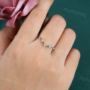 K&ouml;nnte beinhalten: Ein zarter Silberring mit einem V-f&ouml;rmigen Design, das mit kleinen gr&uuml;nen Edelsteinen und wei&szlig;en Diamanten besetzt ist.