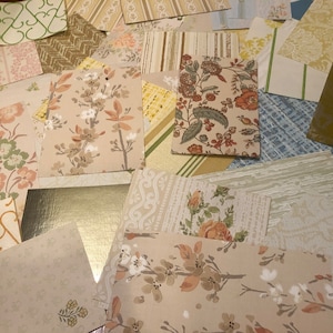 May include: A collection of vintage wallpaper samples in various patterns and colors, including floral, geometric, and striped designs. The samples are arranged in a random pattern on a brown surface.
