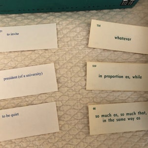 以下が含まれることがあります： 青い文字が書かれた白いインデックスカードが5枚。カードには、821、756、559、822、746、66と番号が振られています。カードに書かれた文章は、「to invite」、「whatever」、「in proportion as, while」、「president (of a university)」、「to be quiet」、「so much as, so much that, in the same way as」です。