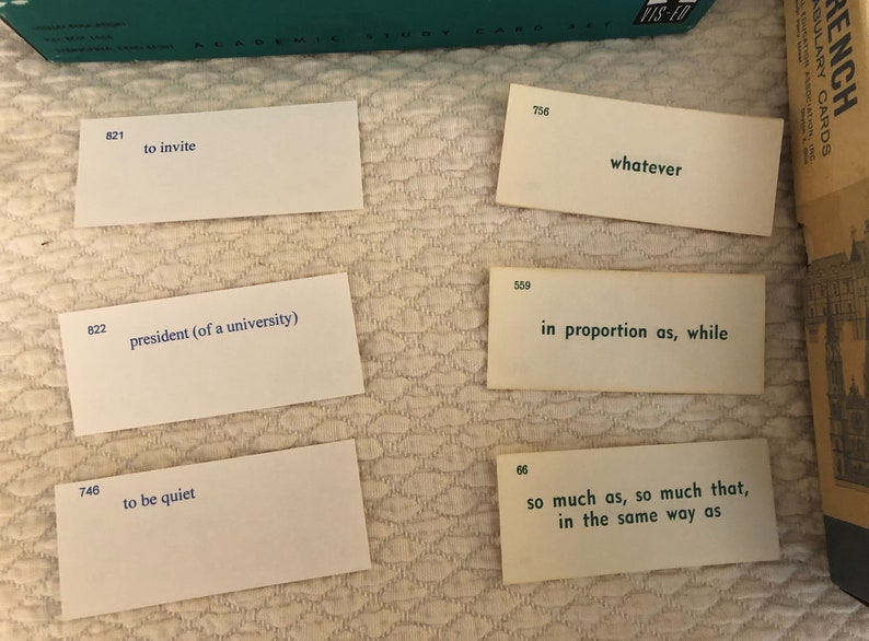 以下が含まれることがあります： 青い文字が書かれた白いインデックスカードが5枚。カードには、821、756、559、822、746、66と番号が振られています。カードに書かれた文章は、「to invite」、「whatever」、「in proportion as, while」、「president (of a university)」、「to be quiet」、「so much as, so much that, in the same way as」です。