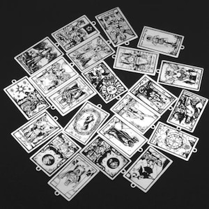 May include: A set of 20 silver-toned metal charms featuring black and white illustrations of tarot cards. The charms are in the shape of rectangles with rounded corners and have a hole at the top for attaching to a chain or bracelet.
