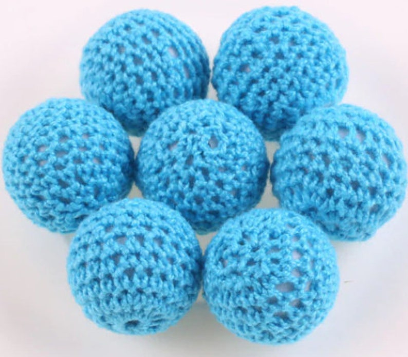 May include: Seven crocheted balls in a light blue color. The balls are made of a fine, open weave crochet thread.