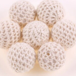 May include: Seven white crocheted balls, each with a delicate, intricate pattern. The balls are arranged in a circular pattern, creating a visually appealing and textured design.