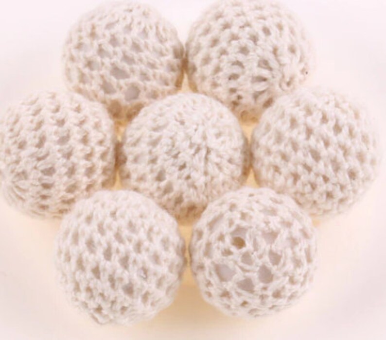 May include: Seven white crocheted balls, each with a delicate, intricate pattern. The balls are arranged in a circular pattern, creating a visually appealing and textured design.