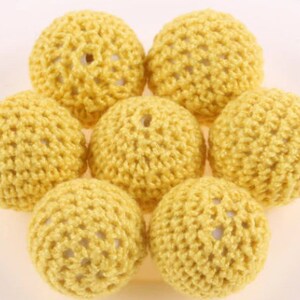 May include: Seven yellow crocheted balls with a textured surface.