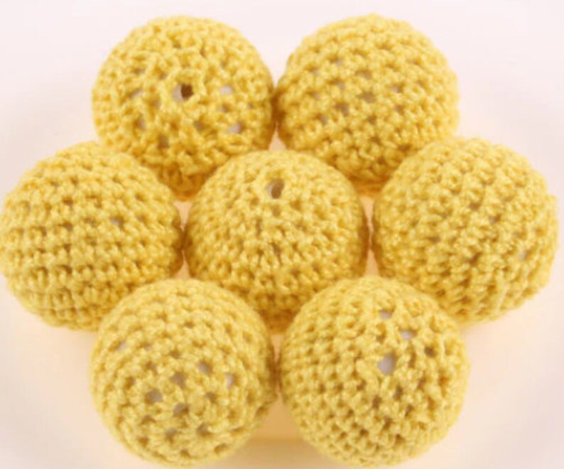 May include: Seven yellow crocheted balls with a textured surface.