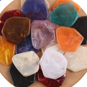 May include: Assortment of colorful, irregular shaped, translucent resin pieces. The pieces are in various shades of blue, green, orange, yellow, brown, purple, white, and black.