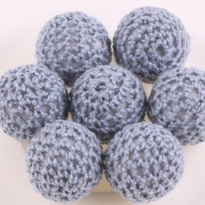 May include: A set of seven crocheted balls in a light blue color. The balls are made with a delicate, openwork pattern.