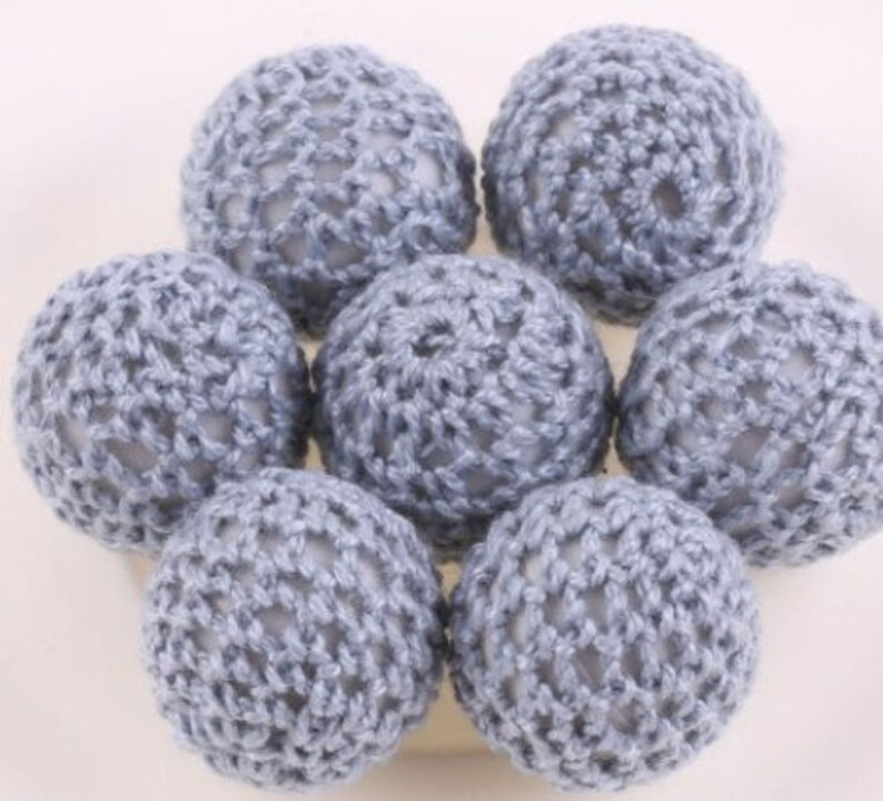 May include: A set of seven crocheted balls in a light blue color. The balls are made with a delicate, openwork pattern.