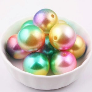 May include: A bowl of iridescent rainbow colored plastic beads. The beads are round and have a pearlescent finish.