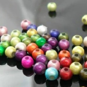 May include: A collection of colorful round beads with a pearlescent finish. The beads are various shades of green, blue, red, purple, pink, and white.