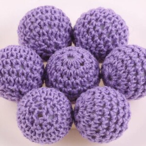 May include: A set of eight purple crocheted balls. The balls are made of a soft, textured yarn and have a delicate, lacy appearance.