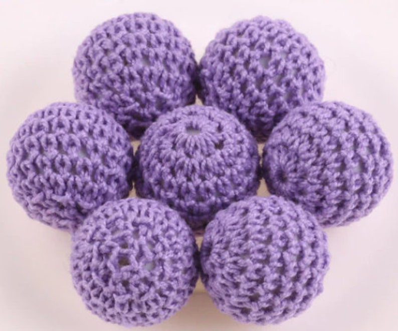 May include: A set of eight purple crocheted balls. The balls are made of a soft, textured yarn and have a delicate, lacy appearance.