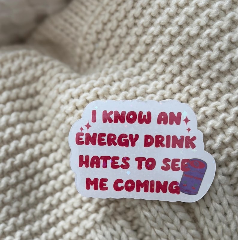 May include: White sticker with pink text that reads "I know an energy drink hates to see me coming". The sticker has a small purple and white can illustration.