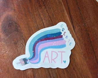 May include: A colorful sticker with the words "CREATE ART" in a whimsical font. The design features a paintbrush with streaks of blue, purple, and pink, creating a vibrant and artistic visual.
