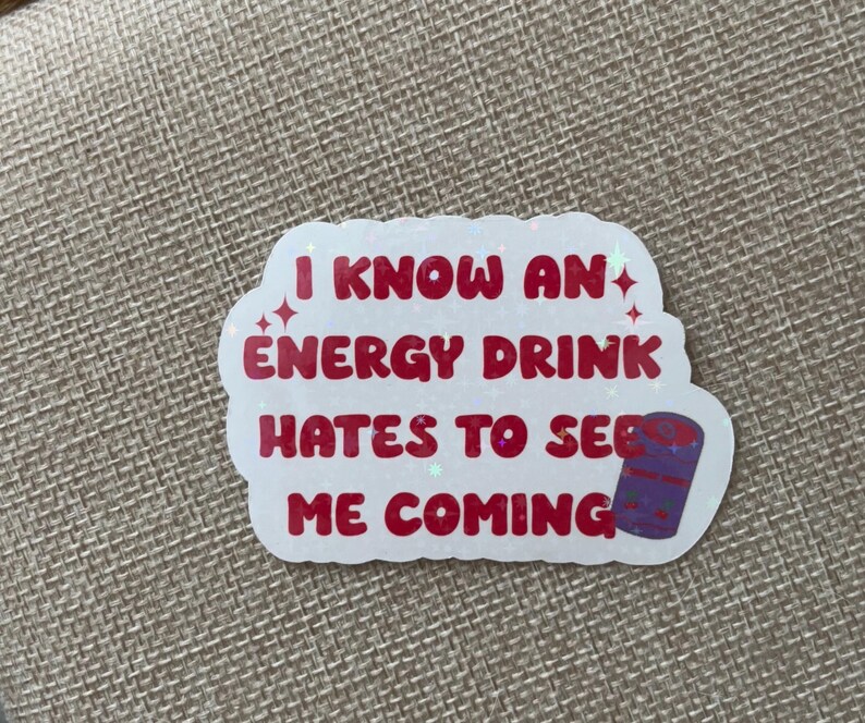 May include: White sticker with red text that reads "I know an energy drink hates to see me coming". A purple and white can is pictured next to the text.