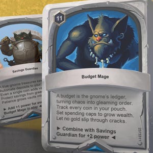 Könnte beinhalten: Eine Fantasy-Kartenspielkarte mit blauem Hintergrund und einer Cartoon-Illustration einer grünen Goblin-ähnlichen Kreatur mit einer Knochenkette. Die Karte trägt den Titel "Budget Mage" und hat die Nummer 11 in der oberen linken Ecke. Der Kartentext lautet: "Ein Budget ist das Buch des Gnoms, das Chaos in strahlenden Glanz verwandelt. Verfolge jede Münze in deiner Tasche. Setze Ausgabenlimits, um Reichtum zu vermehren. Lass kein Gold durch Risse fallen." Die Karte hat auch ein kleines Symbol in der unteren linken Ecke, das "Kombinieren mit Savings Guardian für +2 Power" sagt.
