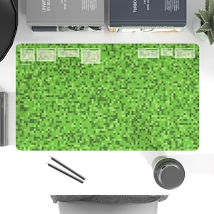 Puede incluir: Una alfombrilla de escritorio verde pixelada con un borde blanco. La alfombrilla tiene un patrón repetitivo de pequeños cuadrados verdes.