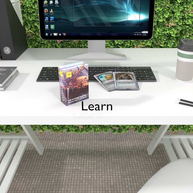 May include: A white desk with a computer monitor, keyboard, a box of "Javascript: The Good Parts" cards, and three playing cards. The desk is in front of a green wall.