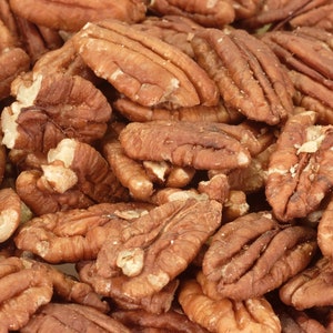 Puede incluir: Una imagen de primer plano de un montón de mitades de nuez de nogal. Las nueces de nogal son de color marrón claro y tienen una textura ligeramente rugosa.