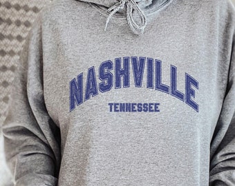 May include: A gray hooded sweatshirt with the text "NASHVILLE TENNESSEE" in blue embroidered lettering.