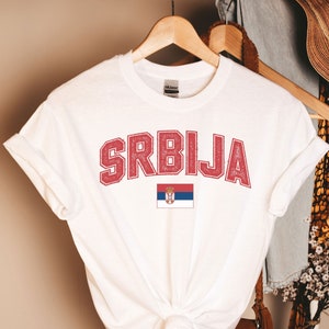 May include: White t-shirt with a red vintage-style graphic that says "SRBIJA" and a small image of the Serbian flag.