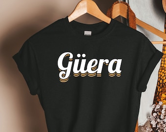 May include: Black t-shirt with the word "Giuera" printed in white with a yellow outline in a retro font.