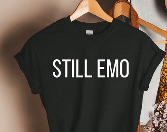 May include: Black t-shirt with the text "STILL EMO" printed in white on the front.