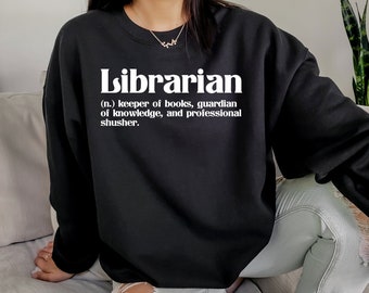 Puede incluir: Una sudadera negra con texto blanco que dice "Bibliotecario (n.) guardián de libros, guardián del conocimiento y profesional del silencio."