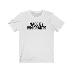 May include: White t-shirt with black text that reads "MADE BY IMMIGRANTS".