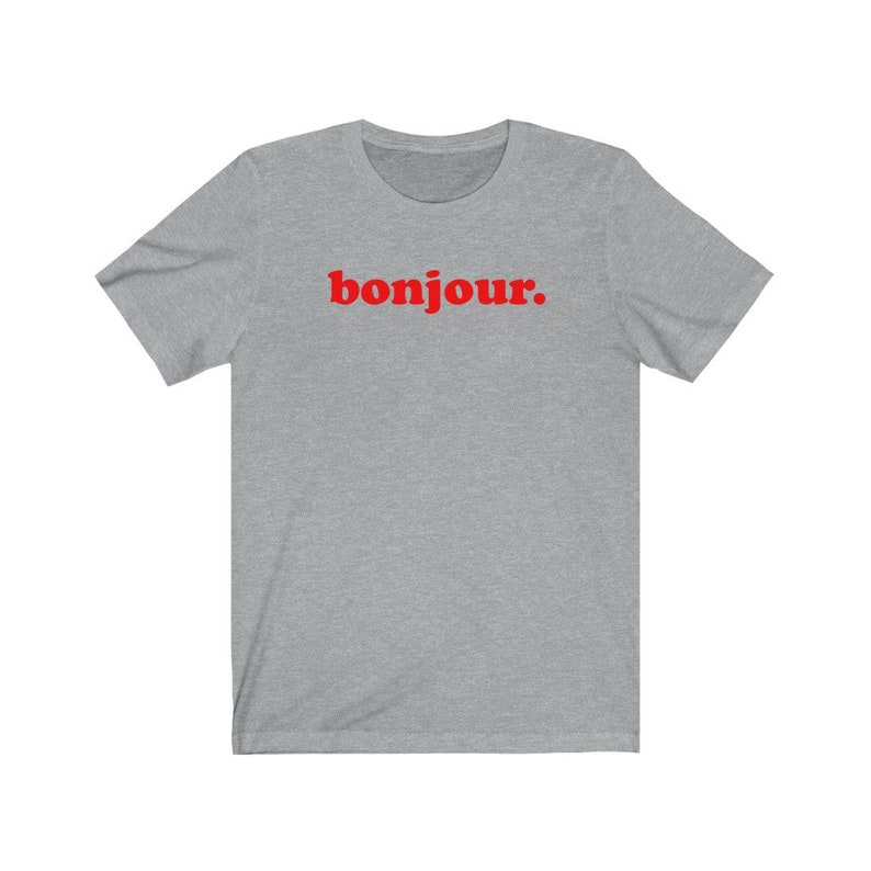 Pode incluir: Uma camiseta cinza mescla com a palavra "bonjour" impressa em vermelho.