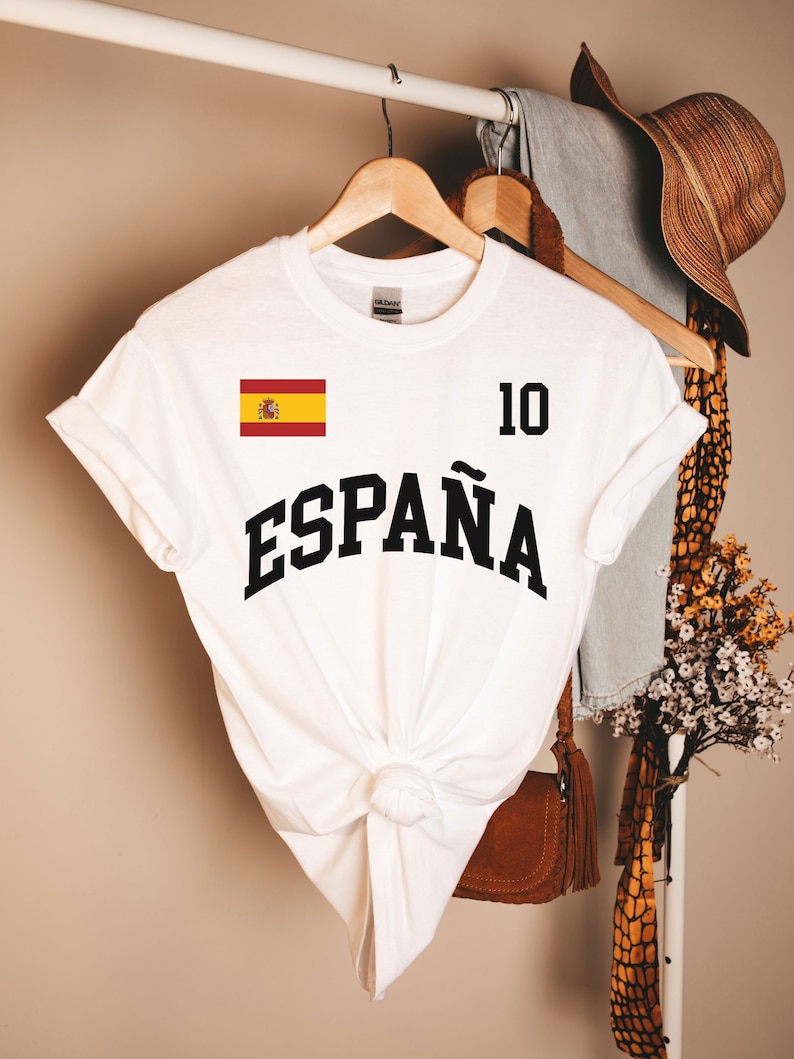 May include: White t-shirt with a black print of the Spanish flag and the word "ESPA&Ntilde;A" with the number "10" above it.
