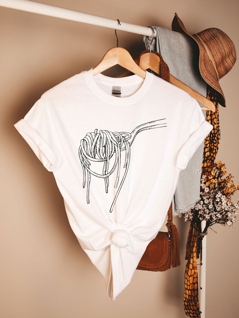 Op de afbeelding: Wit T-shirt met een zwarte lijntekening van spaghetti op een lepel.