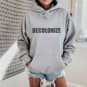 May include: A gray hooded sweatshirt with the word "DECOLONIZE" printed in black on the front.