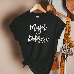 May include: Black t-shirt with white text that reads "mujer poderosa" which translates to "powerful woman" in English.