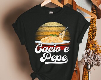 Könnte beinhalten: Schwarzes T-Shirt mit einem Retro-Sonnenuntergang-Motiv und einem Teller Cacio e Pepe Pasta. Der Text "Cacio e Pepe" ist in einer weißen Retro-Schrift.