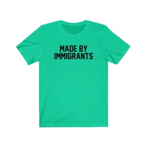 May include: A bright green t-shirt with the text "MADE BY IMMIGRANTS" printed in black.