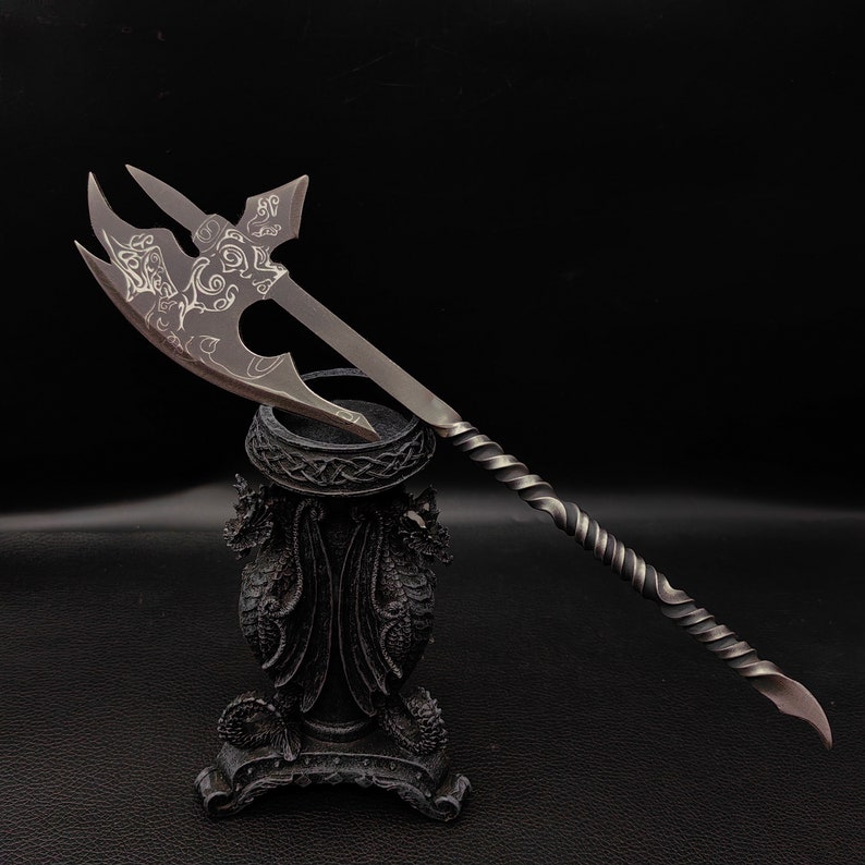May include: A silver axe with a twisted handle and intricate etched designs on the blade, displayed on a black dragon-shaped stand.