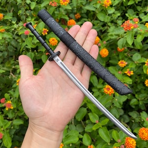 Könnte beinhalten: Ein schwarzes und silbernes Taschenmesser mit einer dekorativen Scheide. Die Scheide hat ein Blumenmuster.