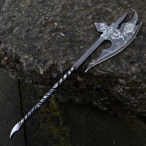 May include: A black axe with a twisted handle and intricate etched designs. The axe head has a double-bladed design with a pointed tip.