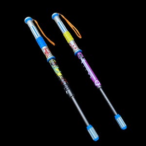 May include: Two colorful bubble wands with a black background. One wand is blue, yellow, and red, and the other is purple and yellow. Each wand has a silver handle and a blue and white striped tip. Both wands have an orange string attached.