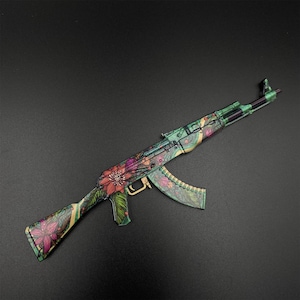 Puede incluir: Un rifle estilo AK-47 con un dise&ntilde;o floral. El rifle presenta un patr&oacute;n floral verde, beige y morado. El cargador y el ca&ntilde;&oacute;n son verdes y negros. El fondo es gris oscuro.