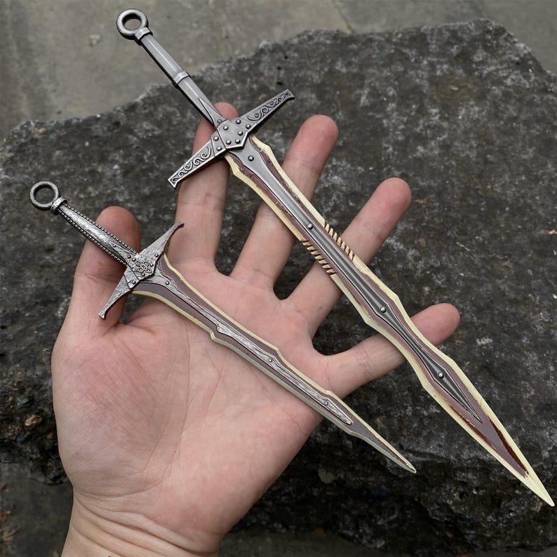 May include: Two decorative swords with silver blades and ornate crossguards. The larger sword is approximately 12 inches long, and the smaller one is about 6 inches. Both have a brown and cream colored design on the blade.
