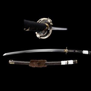 May include: A Japanese katana sword with a curved, polished steel blade. The handle is wrapped in black fabric, and the guard features a decorative design. The scabbard is dark brown with a fur accent and white wrapping.