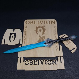May include: A fantasy sword with a bright blue blade and ornate silver hilt, resting on a wooden display stand. The stand features the word "OBLIVION" and a logo. The sword is approximately 24 inches long.